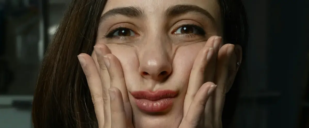 woman squeezing cheeks between two hands looking at camera