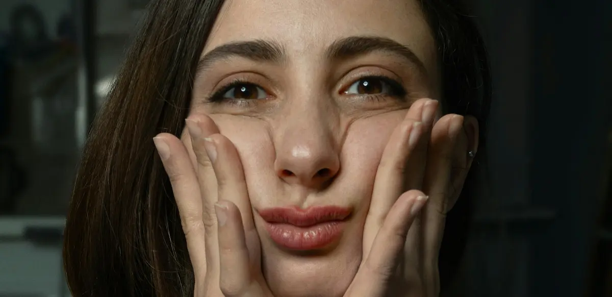 woman squeezing cheeks between two hands looking at camera